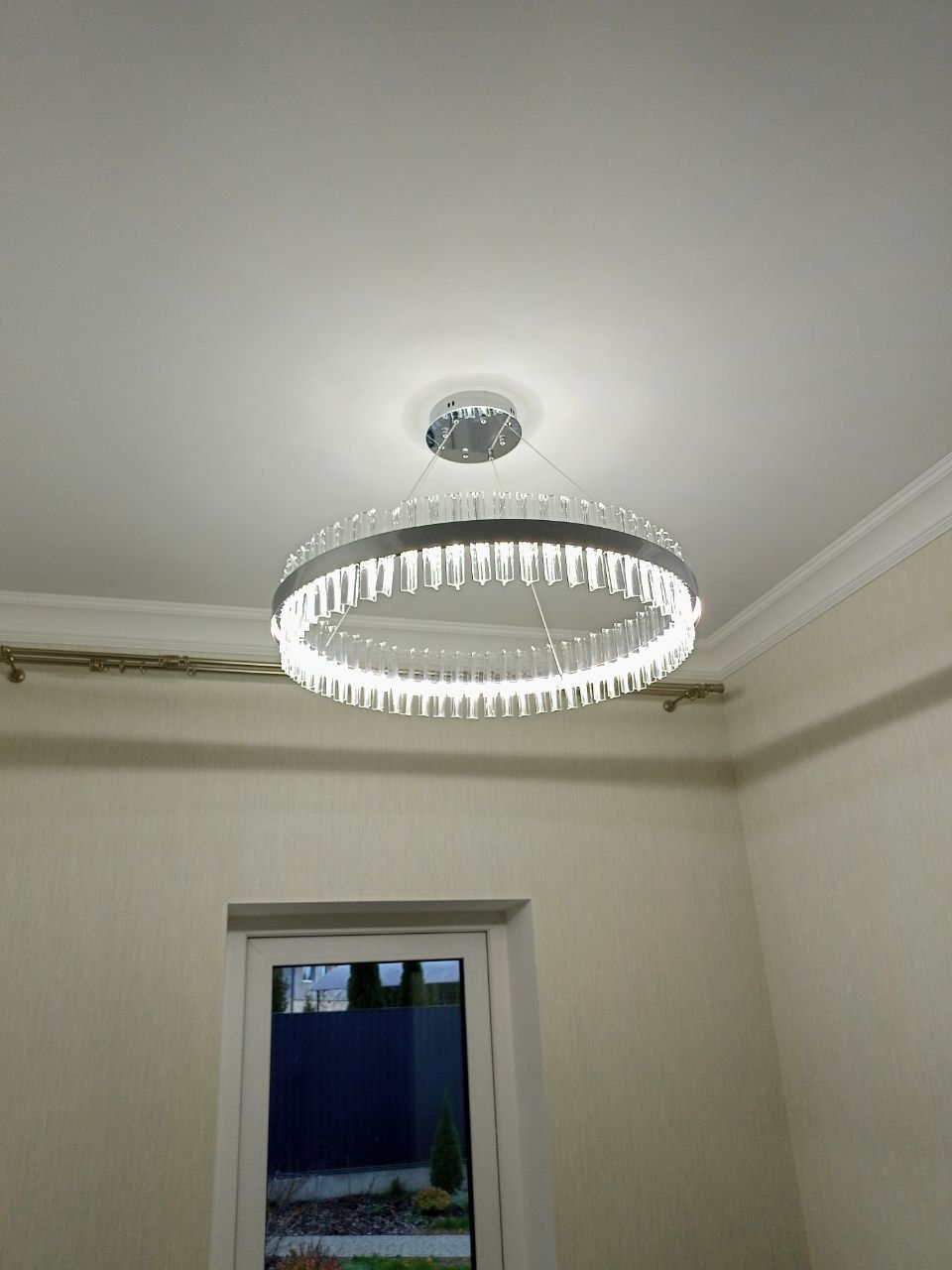 A modern, circular LED chandelier brightly illuminates a white ceiling with its sleek design.