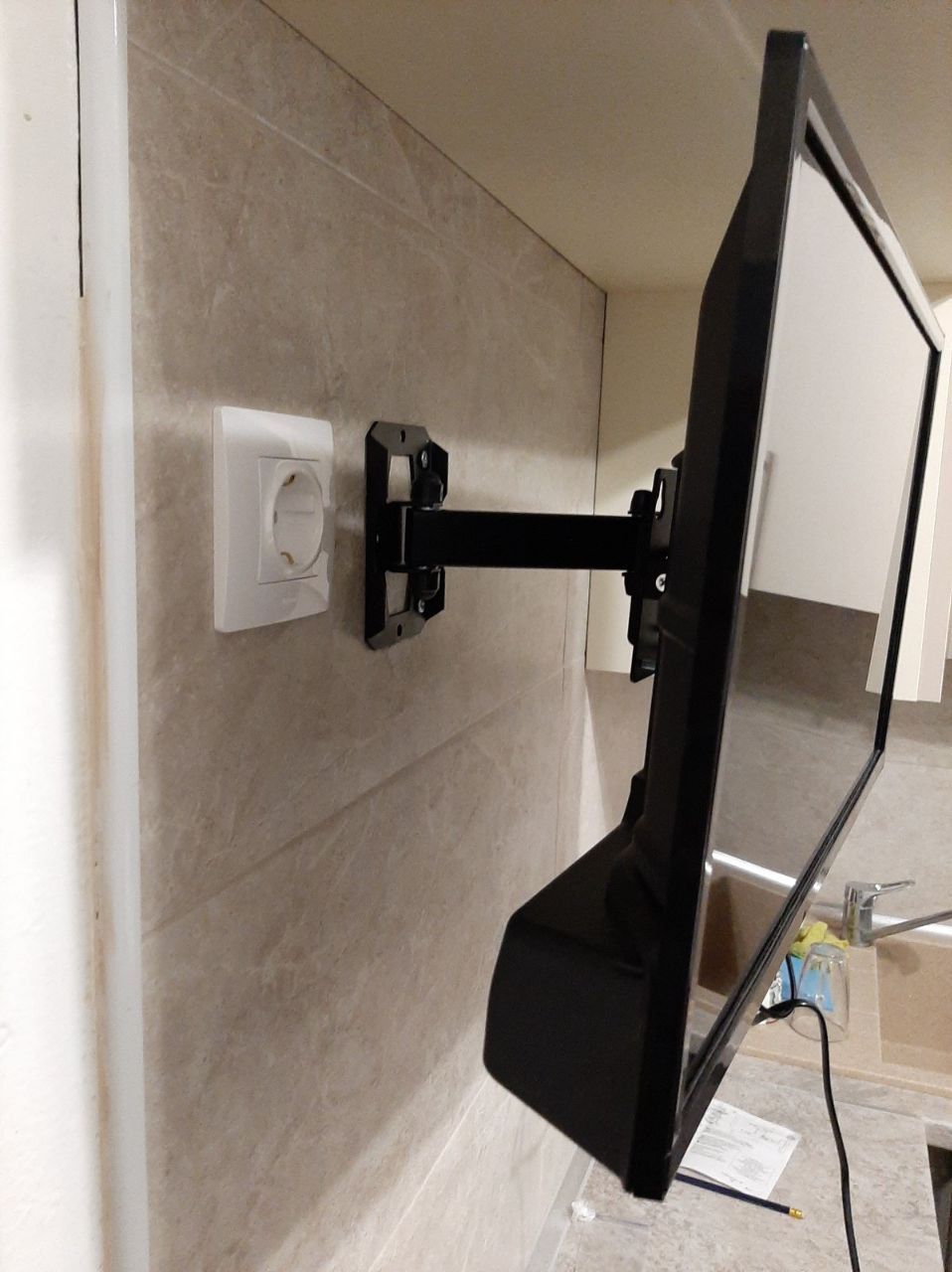 Flat-screen TV mounted on a wall bracket next to a power outlet.