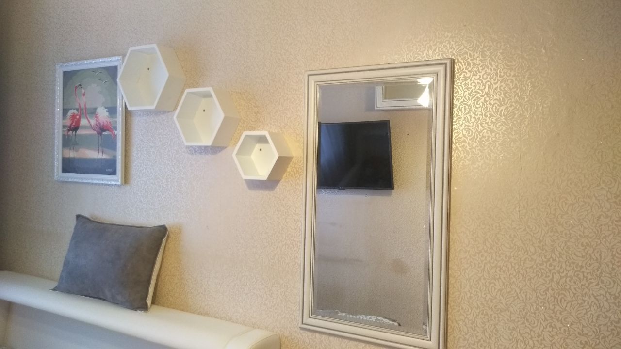 Modern decorated wall featuring a framed print, hexagonal shelves, a bench, and a mirror.