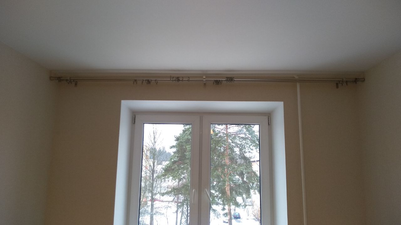 A white-framed window looks out onto snow-covered trees, with a conduit above.