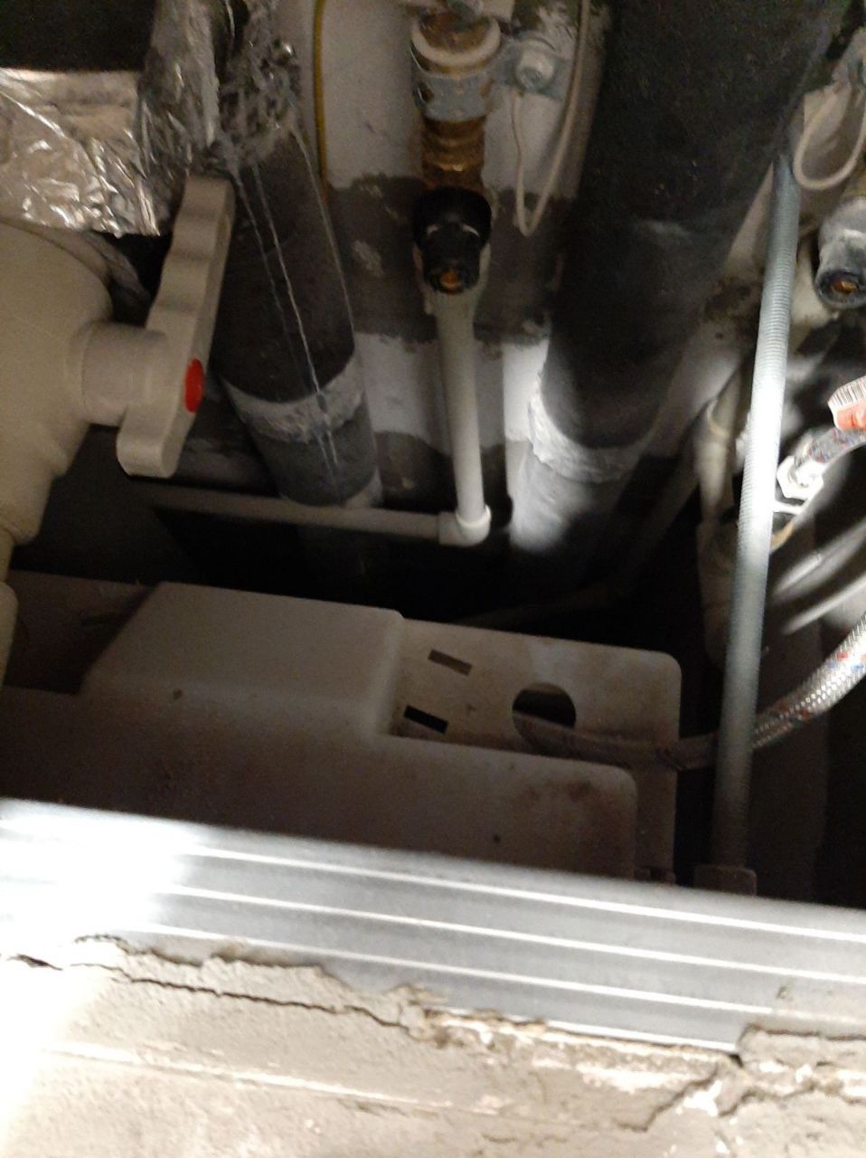 Complex plumbing system with various pipes, wires, and a central valve in a utility space.