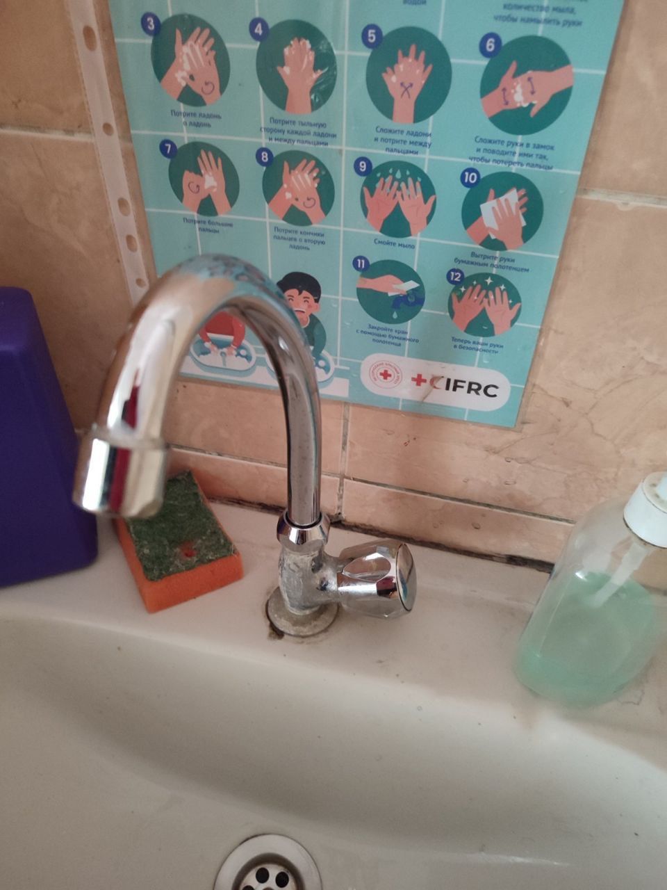 Chrome faucet above a white sink with a handwashing guide poster in the background.