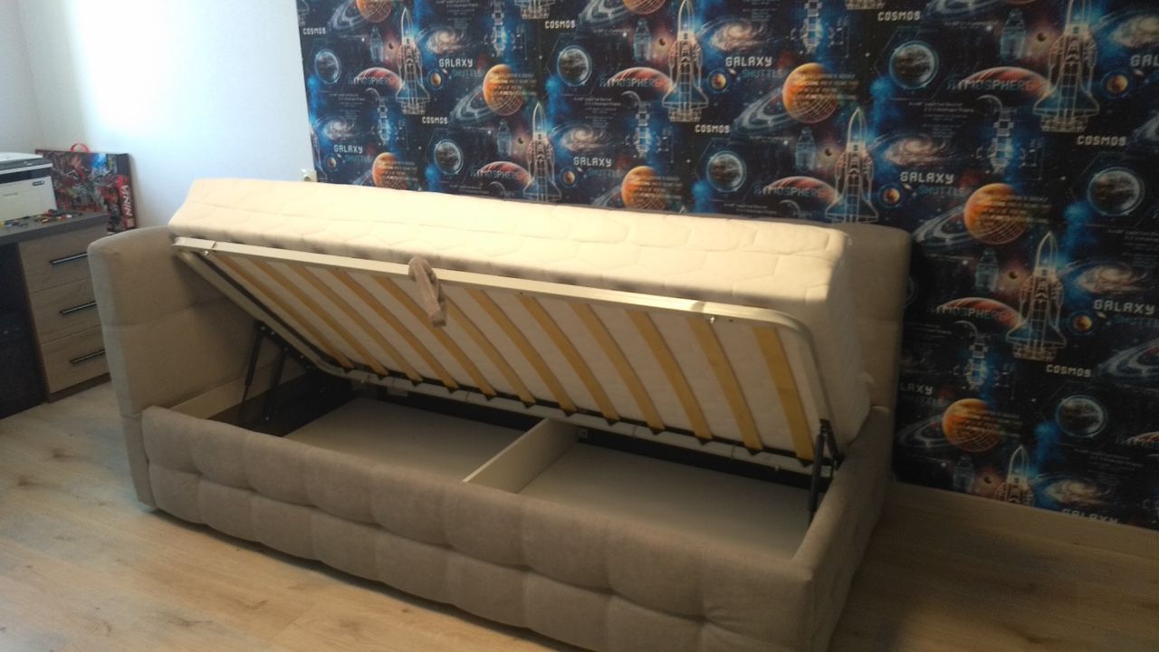 Grey sofa bed with its seat lifted to reveal a spacious storage compartment underneath.